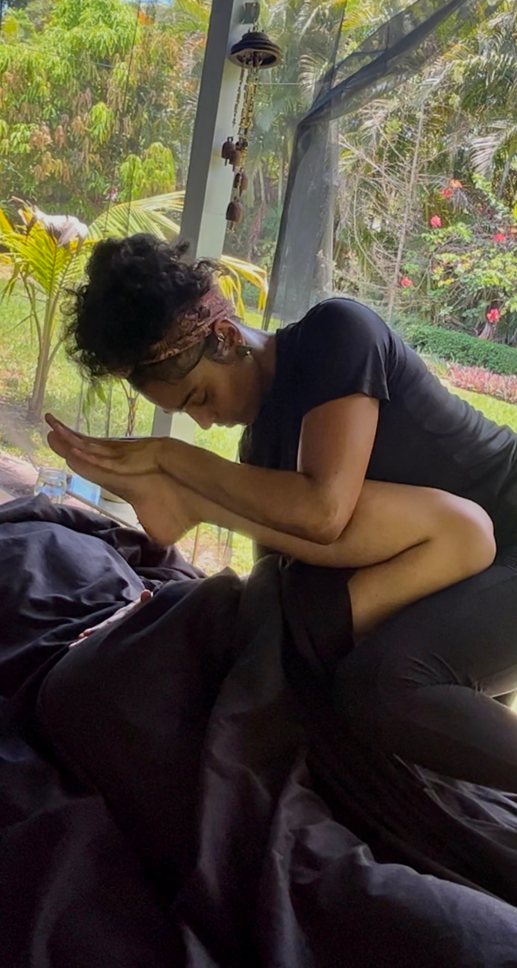 Iris giving a massage beside garden windows surrounded by greenery